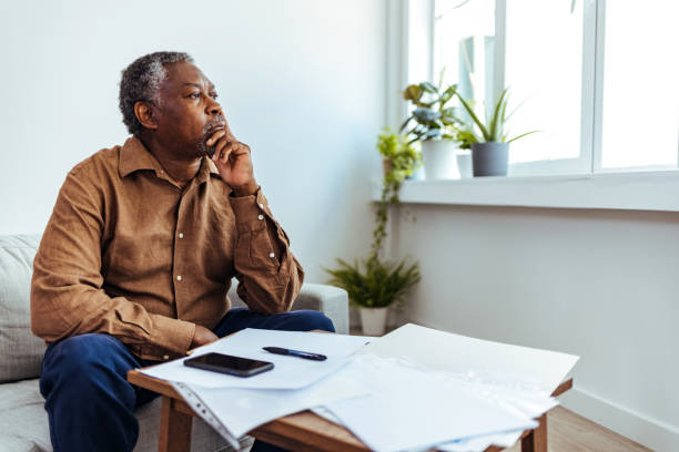 depressed senior adult man with stacks of papers and envelopes